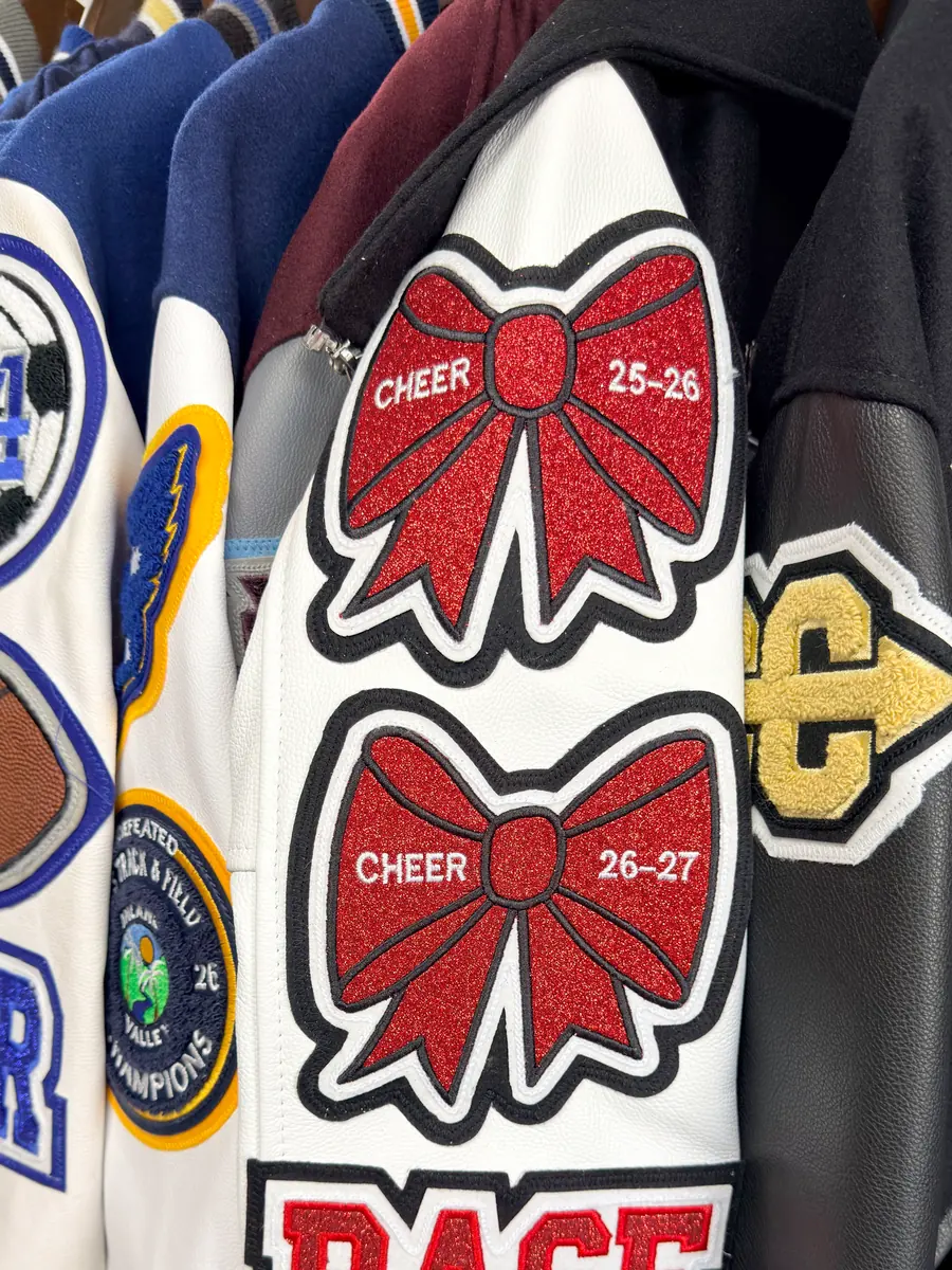 Custom letterman jacket sleeve with red glitter cheer bows and BASE patches