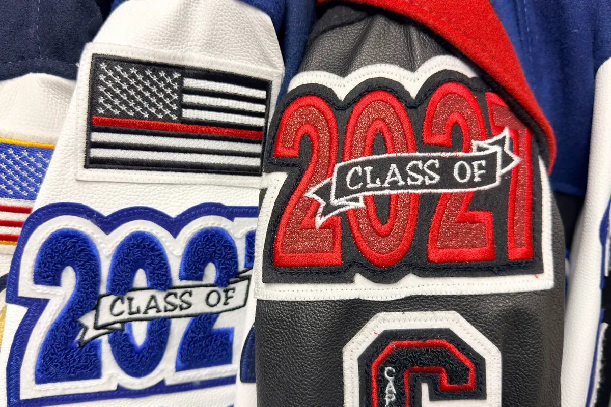 Close-up of red and blue chenille graduation-year patches sewn onto letterman jacket sleeves